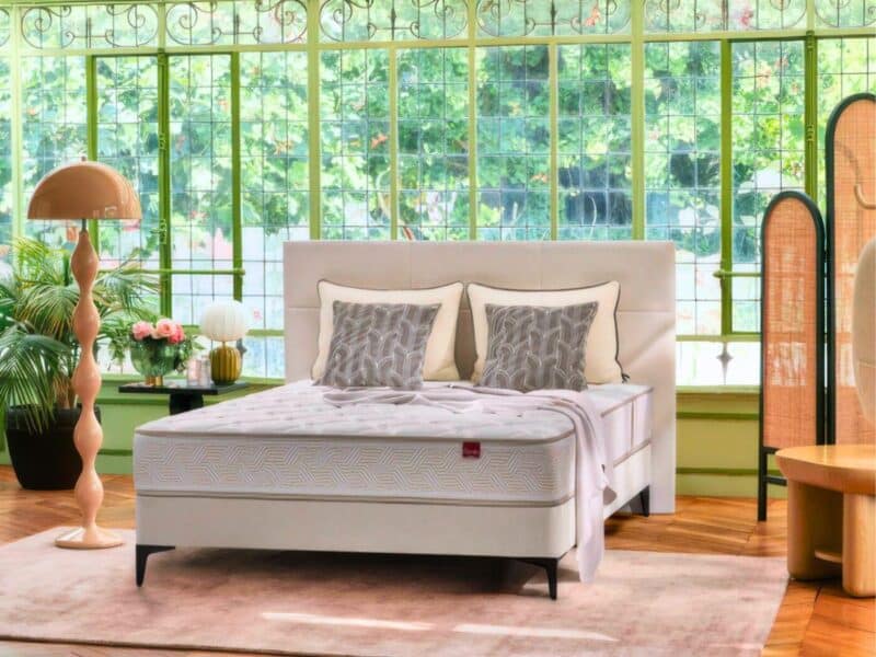 a bed with pillows in a room with windows