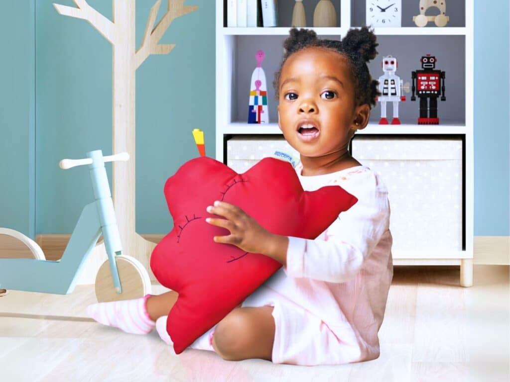 Enfant tenant coussin cœur Vitafoam, collection maternité accessoires chambre enfant Madagascar