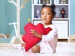 Enfant tenant coussin cœur Vitafoam, collection maternité accessoires chambre enfant Madagascar