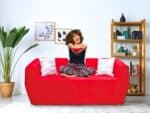 Femme sur canapé rouge Vitafoam, collection POLLUX mobilier enfant confortable coloré