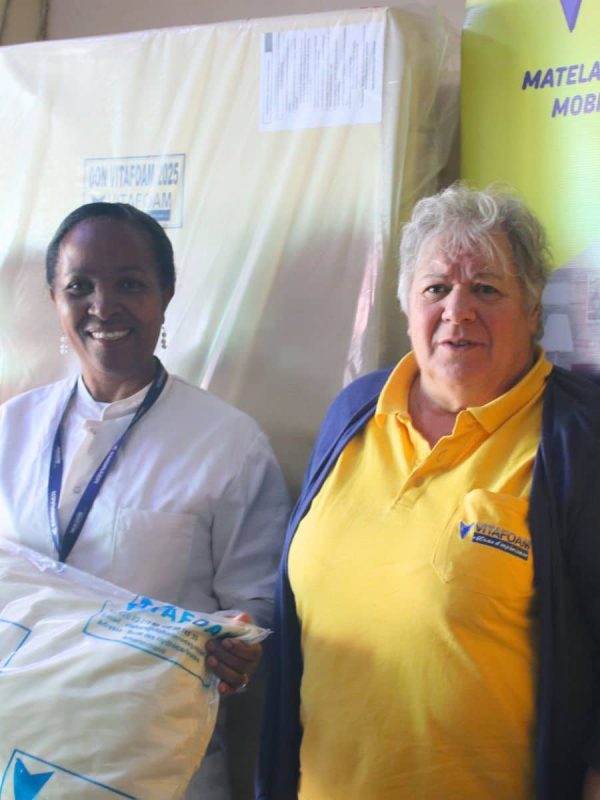 Employée Vitafoam uniforme jaune présentant matelas emballé, fabrication locale qualité Madagascar