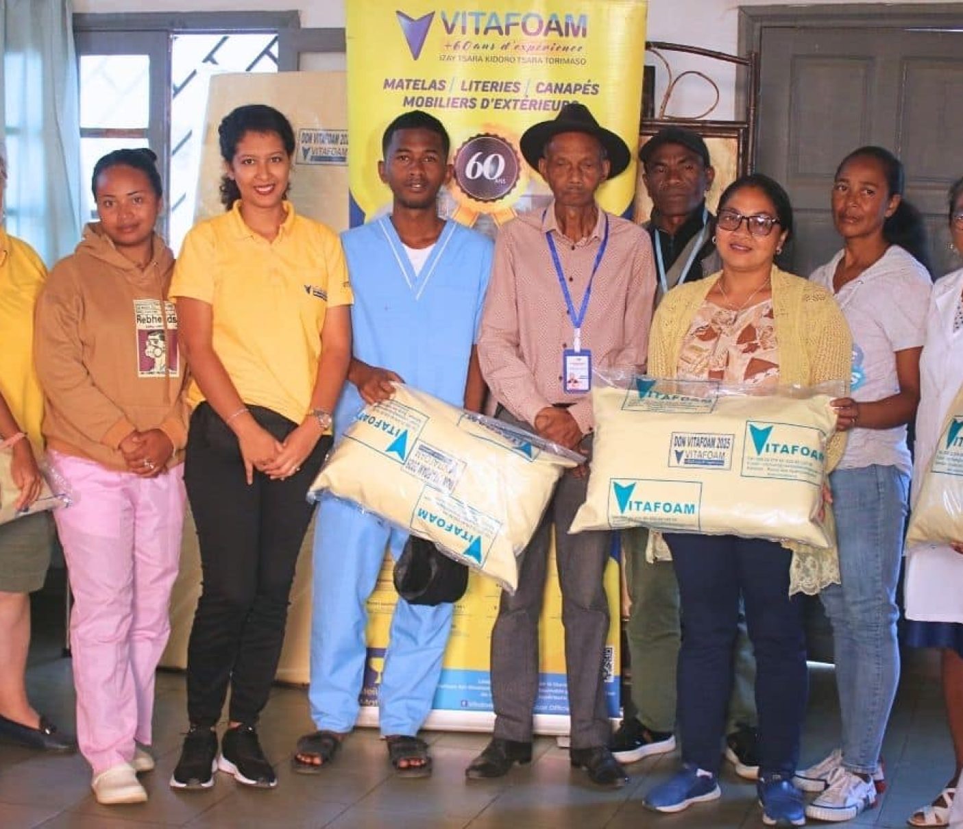 Équipe Vitafoam uniformes jaunes présentant produits, fabrication matelas Madagascar qualité locale